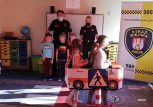 Dzieci w makietach pojazdów poruszają się po sali przedszkolnej