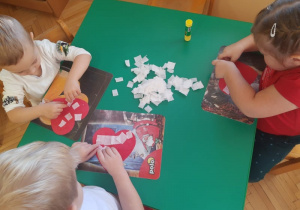 przedszkolaki wyklejające białą bibułą czerwone papierowe serca