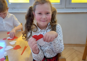 dziewczynka trzymająca białe i czerwone papierowe serce