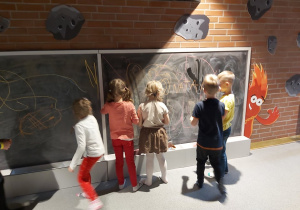 Dzieci rysujące kredą po tablicy.