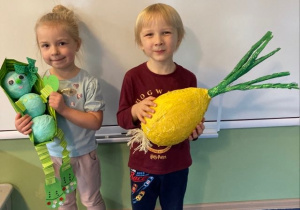dzieci w wykonanymi pracami, Marcelinka trzyma fasolę a Czarek cebulę