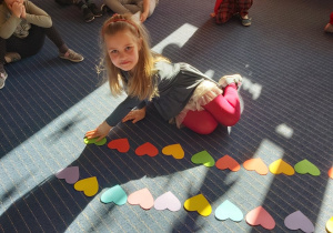 Dziewczynka układaja rytm z kolorowych serduszek.
