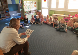 Gość czytający książkę i przedszkolaki.