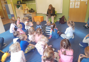 Absolwentka Maja czyta dzieciom książkę.