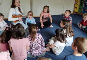Dzieci słuchaja gry na ukulele.
