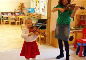 Dziewczynka razem z pania gra na skrzypcach.