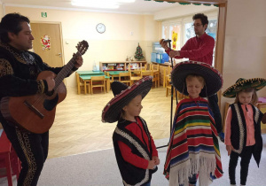Dzieci w meksykańskich przebraniach występują z muzykami.