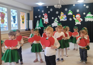 Dzieci tańczą z czerwonymi sercami.