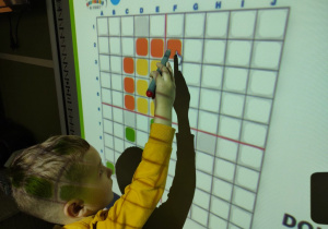 Chłopiec koduje obrazek na tablicy interaktywnej.