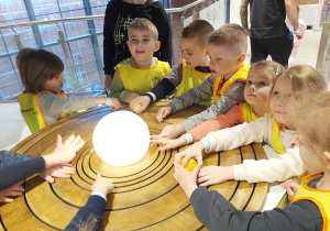 Dzieci podziwiają makietę układu słonecznego.
