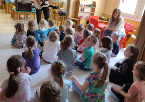 Dzieci słuchają gry na gitarze.