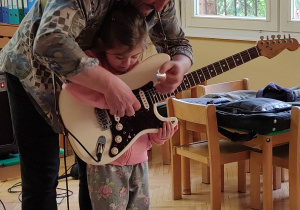 Dziewczynka próbuje grać na gitarze.