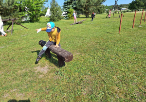 Chłopiec przeskakujący drewnianą przeszkodę.