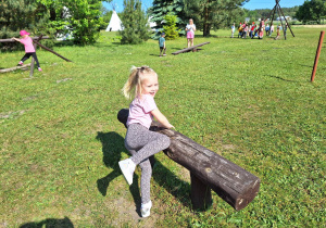 Dziewczynka przeskakująca drewnianą przeszkodę.