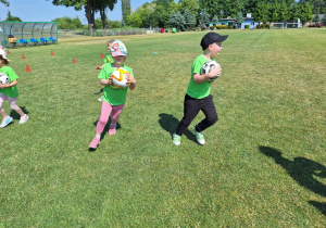 Trzymające piłkę dzieci w czasie biegu.
