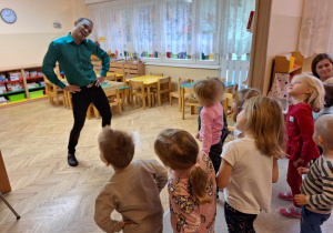 Tancerz pokazuje ruchy taneczne dzieciom.