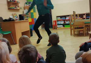 Tancerz pokazuje ruchy taneczne dzieciom.