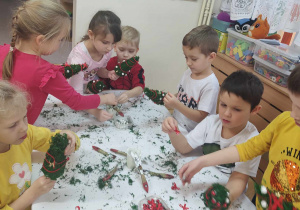 Dzieci dekorują choinki ozdobami.
