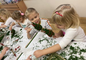 Dzieci dekorują choinki.