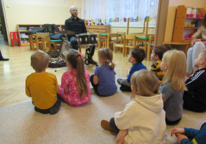 Dzieci słuchają gry na instrumencie.